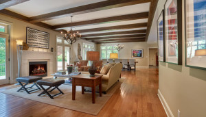 Merion House open-concept renovated family room with glass patio doors, fireplace, and wood ceiling beams in Gladwyne, PA